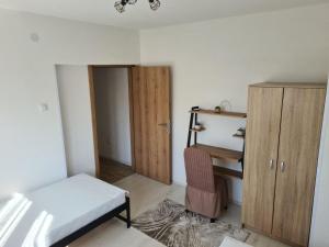 een slaapkamer met een bed, een bureau en een kast bij Sirob bubanj in Kragujevac