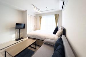a bedroom with a bed and a couch and a tv at toggle BUNKYO KORAKUEN in Tokyo