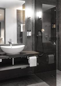 a bathroom with a sink and a shower at AMERON Davos Swiss Mountain Resort in Davos