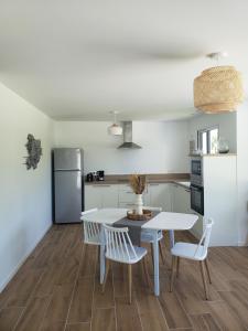 een keuken met een tafel en stoelen en een koelkast bij LA POINTE DE SEL in Fouesnant