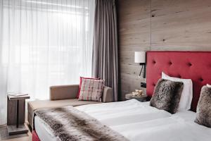 a bedroom with a large bed and a red headboard at AMERON Davos Swiss Mountain Resort in Davos