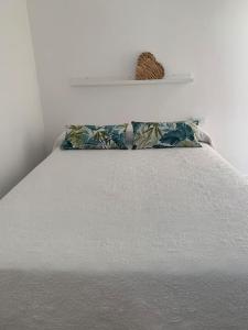 Una cama blanca con dos almohadas encima. en Aloha, en Valdoviño