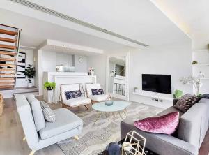 a living room with white furniture and a flat screen tv at Stylish 2 Bed Apt +24/7 Concierge + Pool + Sauna in Sydney