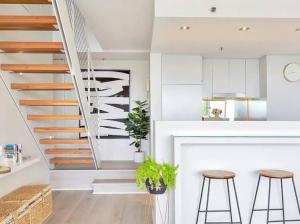 a kitchen with a staircase and two stools at Stylish 2 Bed Apt +24/7 Concierge + Pool + Sauna in Sydney