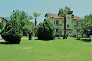 a large yellow house with trees in the yard at Summer Life Villa Apart in Dalyan