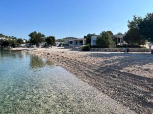 a sandy beach with a house in the background at BUQEZ ECO RESORT - Beach Villas 2 and 8 - Seaview, new wifi! in Drage