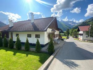 ein weißes Haus mit braunem Dach auf einer Straße in der Unterkunft Alpin Haus Berwang in Berwang