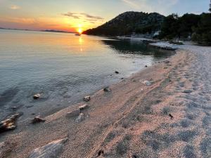 a beach with rocks in the water at sunset at BUQEZ ECO RESORT - Beach Villas 2 and 8 - Seaview, new wifi! in Drage