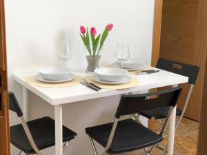 una mesa blanca con platos, vasos y flores. en Apartamentos TravelStep La Latina, en Madrid