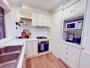 a kitchen with white cabinets and a sink at Patterson Lakes Charming 2 Bedroom House / VPL244 in Patterson Lakes