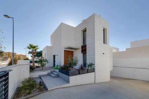 een wit huis met planten aan de zijkant bij Magnífica villa con piscina climatizada in Santiago de la Ribera