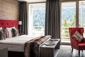 a hotel room with a bed and a red chair at AMERON Davos Swiss Mountain Resort in Davos