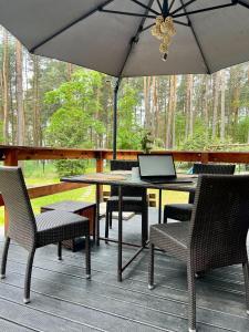 a table and chairs with an umbrella on a deck at Urocza chatka w lesie nad wodą in Skubianka