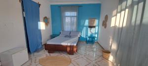 - une chambre avec un lit et un mur bleu dans l'établissement Karibu House, à Paje