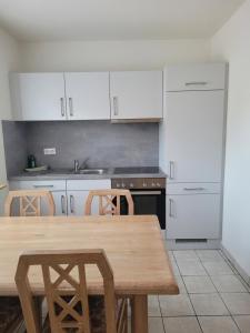 cocina con mesa de madera y armarios blancos en Ferienwohnung in Niebüll, Kreis Nordfriesland, en Niebüll