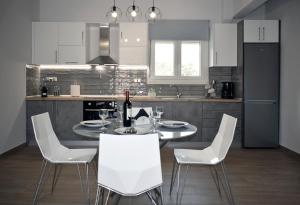 a kitchen with a dining table and white chairs at Thea Home in Nea Karvali