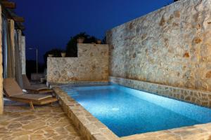 a swimming pool with a stone wall and a blue pool at Villa Vito in Hvar
