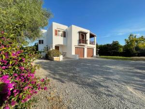 a house with a driveway and some flowers at Authentic Villa with amazing pool in Santa Gertrudis de Fruitera