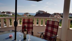 a table with two chairs and wine glasses on a balcony at Villa Stella in Rogoznica