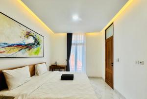 1 dormitorio con 1 cama y una pintura en la pared en Palm&Ocean Canggu, en Canggu