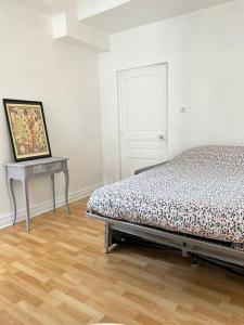 Un dormitorio con una cama y una mesa con una pintura en Agréable gîte au coeur du centre ville 4 personnes, en Chagny