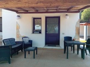 a porch with chairs and tables and a purple door at Casa Marcella in Dorgali