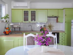 een keuken met groene kasten en een tafel met paarse bloemen bij Apartments Klara in Viganj