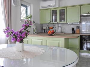 una cucina con armadi verdi e un tavolo con fiori viola di Apartments Klara a Viganj