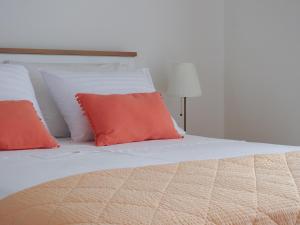 a bed with orange and white pillows on it at Apartments Klara in Viganj