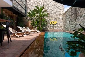 a swimming pool with chairs and a stone building at Hotel Pop Alaçatı in Alaçatı