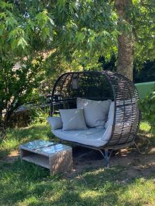 a rattan couch in a garden with a table at Chambre d'hôtes La Chouette in Saint-Martin-du-Puy