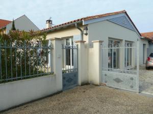 une maison blanche avec un portail et une voiture dans l'établissement Guzzo, à Châtelaillon-Plage