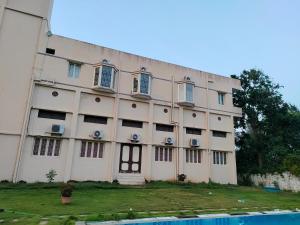 a large white building with windows and a yard at Alegria Resort and SPA, Kovalam in Tirupporūr