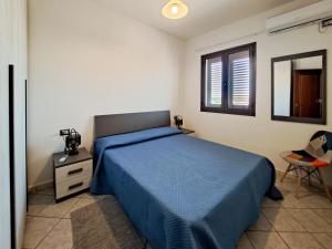 Un dormitorio con una cama azul y una ventana en Appartamento Trilocale vicino al centro di San Teodoro, en San Teodoro