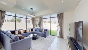 Primestay - Odora 6BR, Akoya Oxygen في دبي: غرفة معيشة مع أريكة زرقاء وتلفزيون