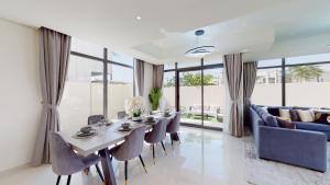 a dining room with a table and chairs and a couch at Primestay - Odora 6BR, Akoya Oxygen in Dubai