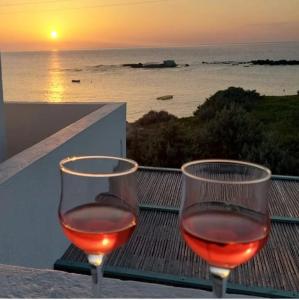 two glasses of wine sitting on a table with the sunset at Anemoessa Studios in Pollonia