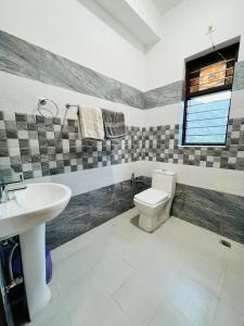 a bathroom with a sink and a toilet and a window at Hotel Anjum Regency in Bajaura