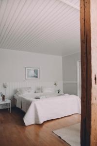 a white bedroom with a large bed with white sheets at Vääksyn Apteekinmajoitus in Vääksy