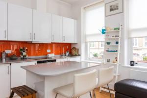 a kitchen with white cabinets and a large island at Homely 1 Bedroom Apartment in the Heart of Vibrant Camden in London