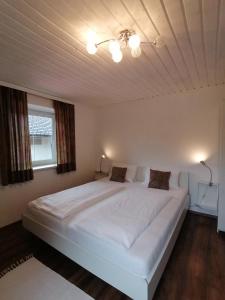 een groot wit bed in een slaapkamer met een plafond bij Steakhouse Fieg in Fuschl am See