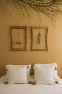 a bed with white pillows and two pictures on the wall at Metzoke Dragot Travelers Village in Metsoke Dragot
