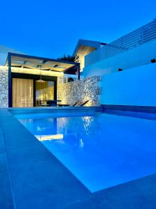 una piscina frente a una casa por la noche en Myrtia Villas III en Anomeriá