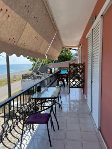 a balcony with tables and chairs and a view of the beach at Eleni Antonouli Rooms in Kokkino Nero