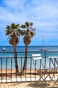 two palm trees on a beach with boats in the water at Le Relais d'Agay in Agay - Saint Raphael