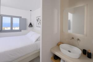 a white bedroom with a bed and a sink at Thoè Oia Suites in Oia