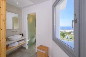 Baño con ventana con vistas al océano en Thoè Oia Suites, en Oia