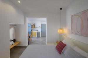 a white bedroom with a bed and a living room at Thoè Oia Suites in Oia