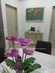 a table with a vase of purple flowers in a room at D'Aisy Homestay Sepang Klia Nilai in Sepang