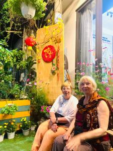 twee oudere vrouwen op een bank in een tuin bij May's House Hoi An in Hội An